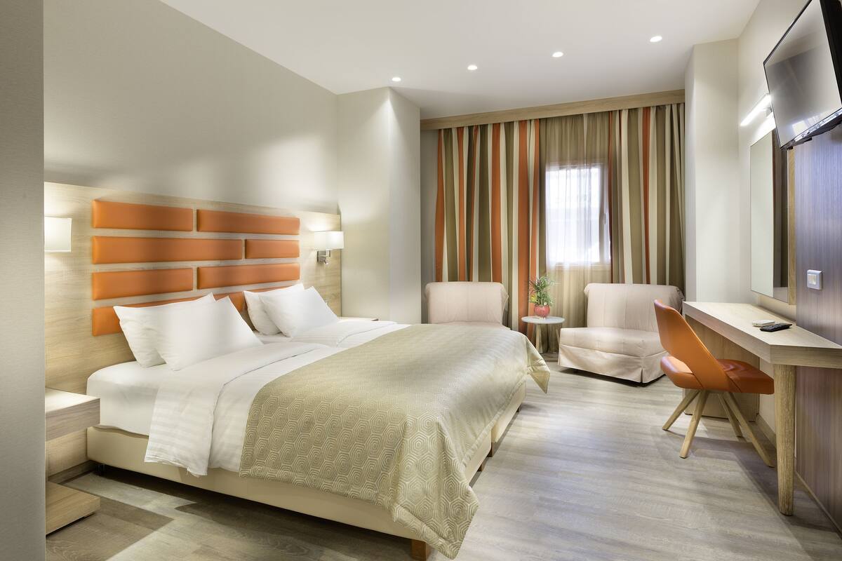 Habitació d'hotel moderna amb un llit gran, una taula de treball, una cadira i una televisió.