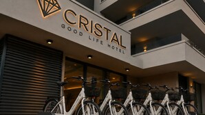 A hotel named 'CRISTAL GOOD LIFE HOTEL' with a modern facade, a row of bicycles, and a closed shutter door. - Hotel Cristal (Sirmione)