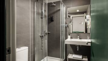 Un baño moderno con cabina de ducha de vidrio, un lavabo blanco y un espejo encima.