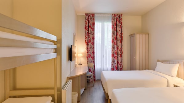 A hotel room with two beds, a desk with a chair, a wardrobe, and a TV mounted on the wall.