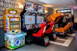 Experience the thrill of racing and gaming at this vibrant arcade, featuring a variety of machines with steering wheels and prize wheels.