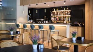Eine moderne Bar mit einer Theke, Barhocker und einer Auswahl an Flaschen.