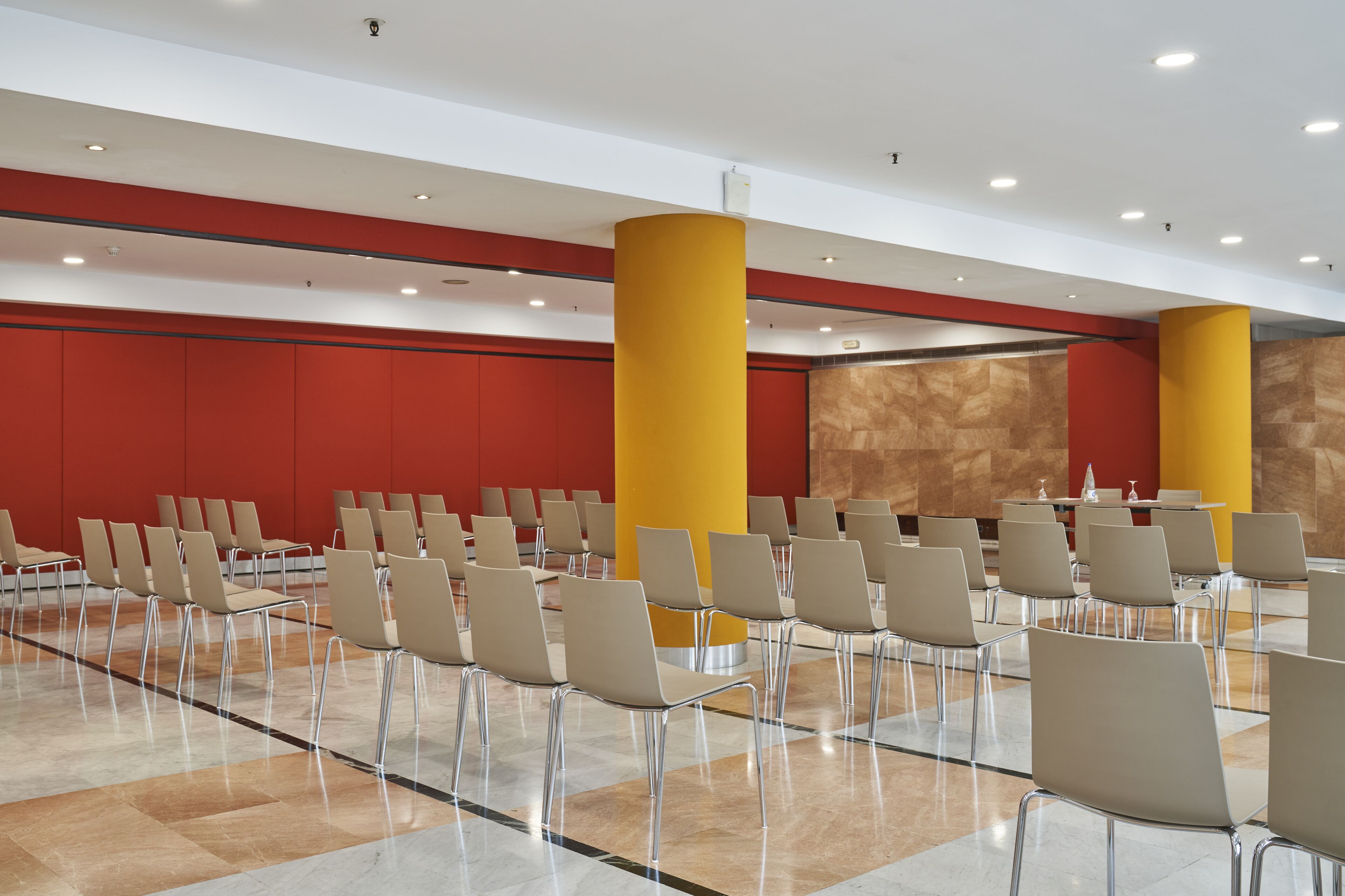 A spacious hall with rows of chairs and a central table, likely for events or meetings.
