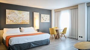 Ein modernes Hotelzimmer mit einem großen Bett, einem Schreibtisch, zwei Stühlen und Kunstwerken an der Wand.