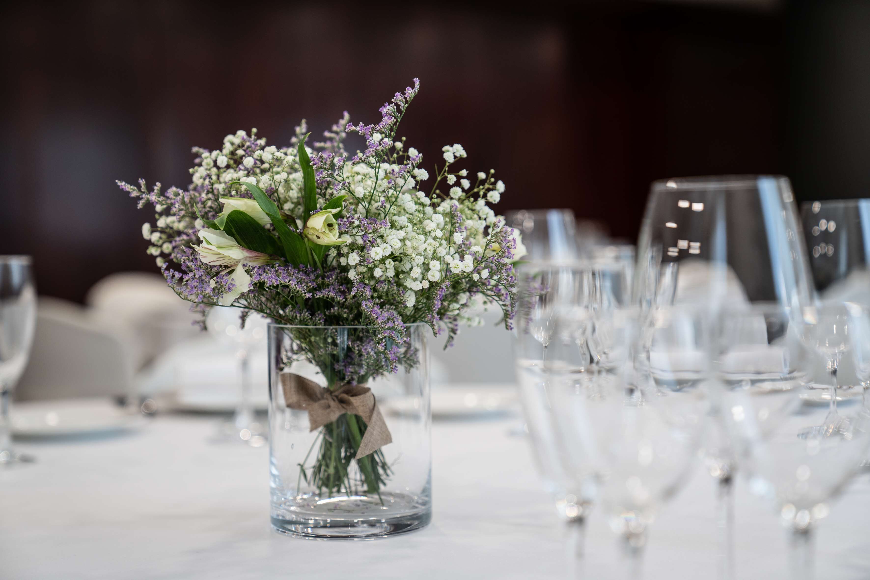 Una mesa dispuesta para comer, con un jarrón de vidrio transparente que contiene un ramo de flores.