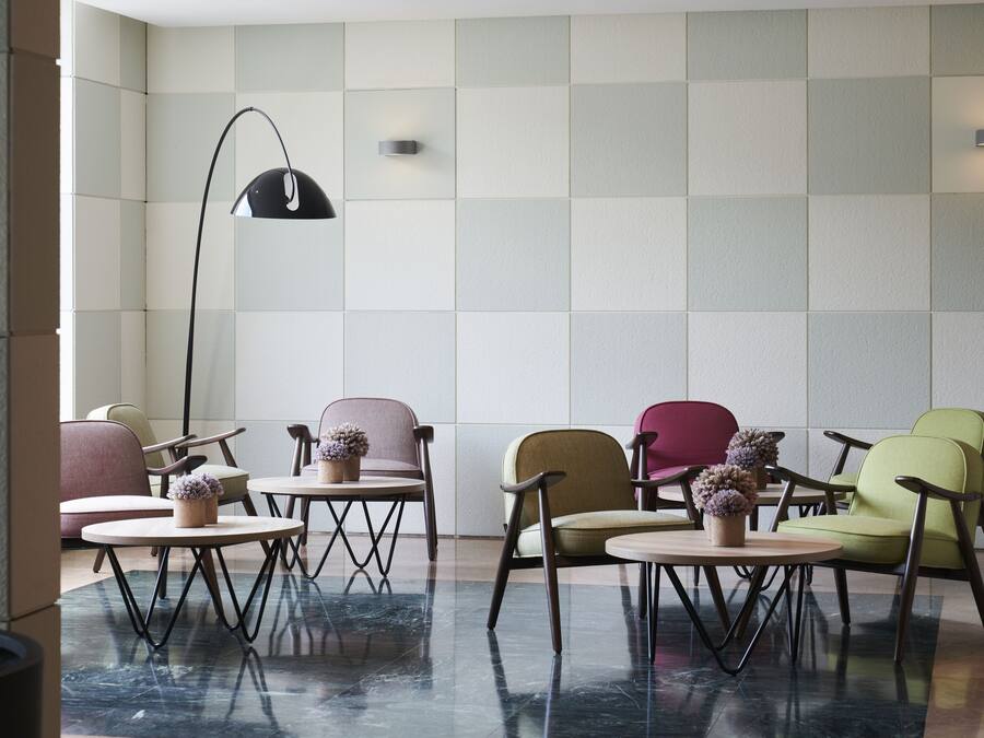 Ein stilvoller Lounge-Bereich mit Schachbrettmuster-Boden, verschiedenen Sitzgelegenheiten und einer Stehlampe.