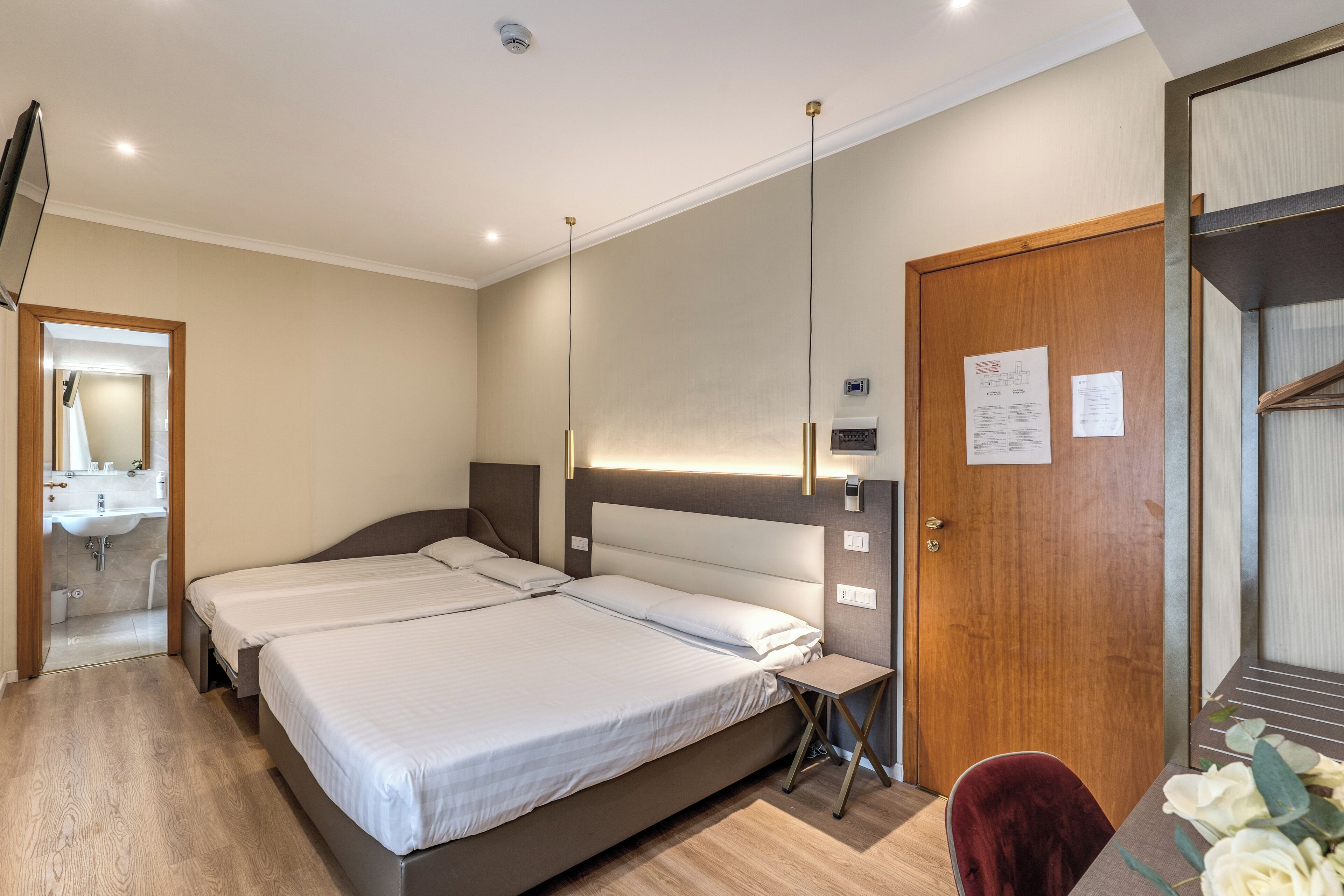 A hotel room with a large bed, bedside tables, a mirror, and a wooden door.