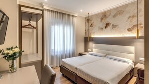 A modern hotel room with a large bed, bedside tables, a desk with a chair, and a hanging wardrobe. - Flower Garden Hotel Rome (Rome)