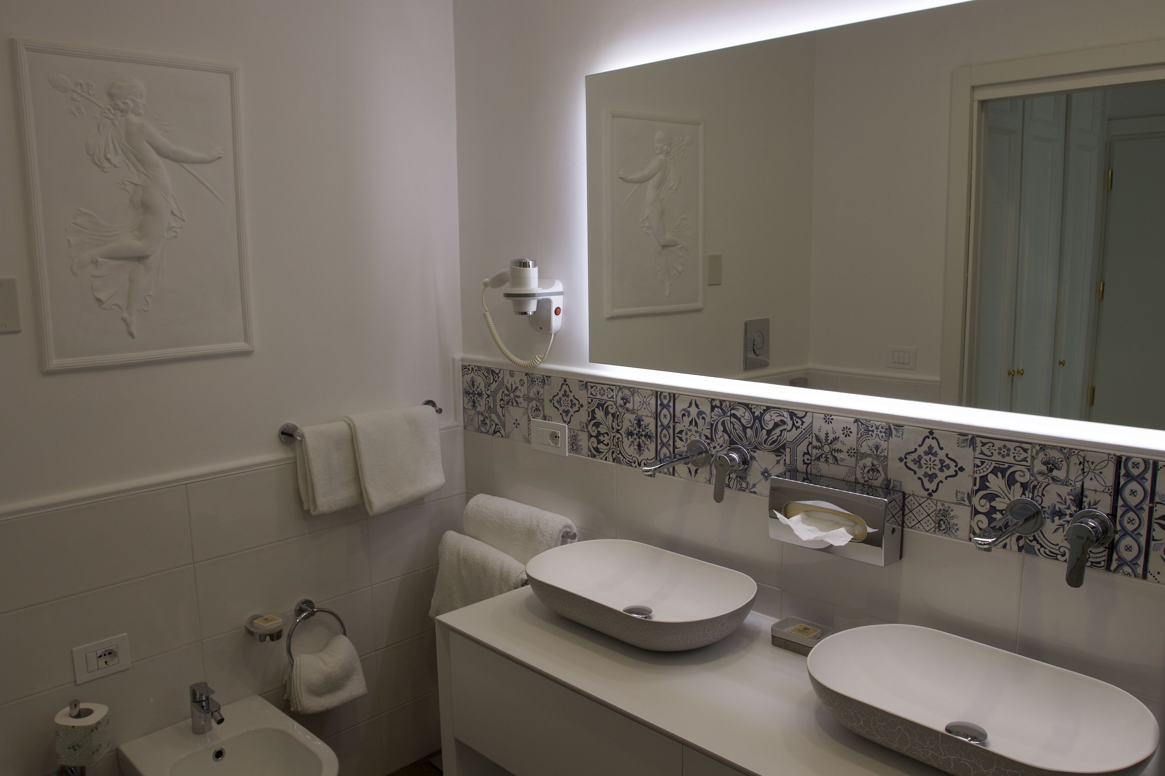 A bathroom with two sinks, a mirror, and decorative wall tiles.