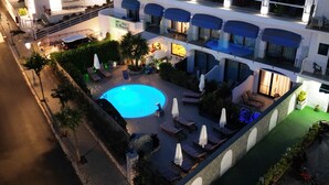 A rooftop pool area with lounge chairs and umbrellas, surrounded by a building with multiple balconies and windows. - Bougainville Luxury Boutique Hotel (Anacapri)