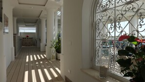 A hallway with a wooden floor, white walls, and a decorative metal gate. - Bougainville Luxury Boutique Hotel (Anacapri)