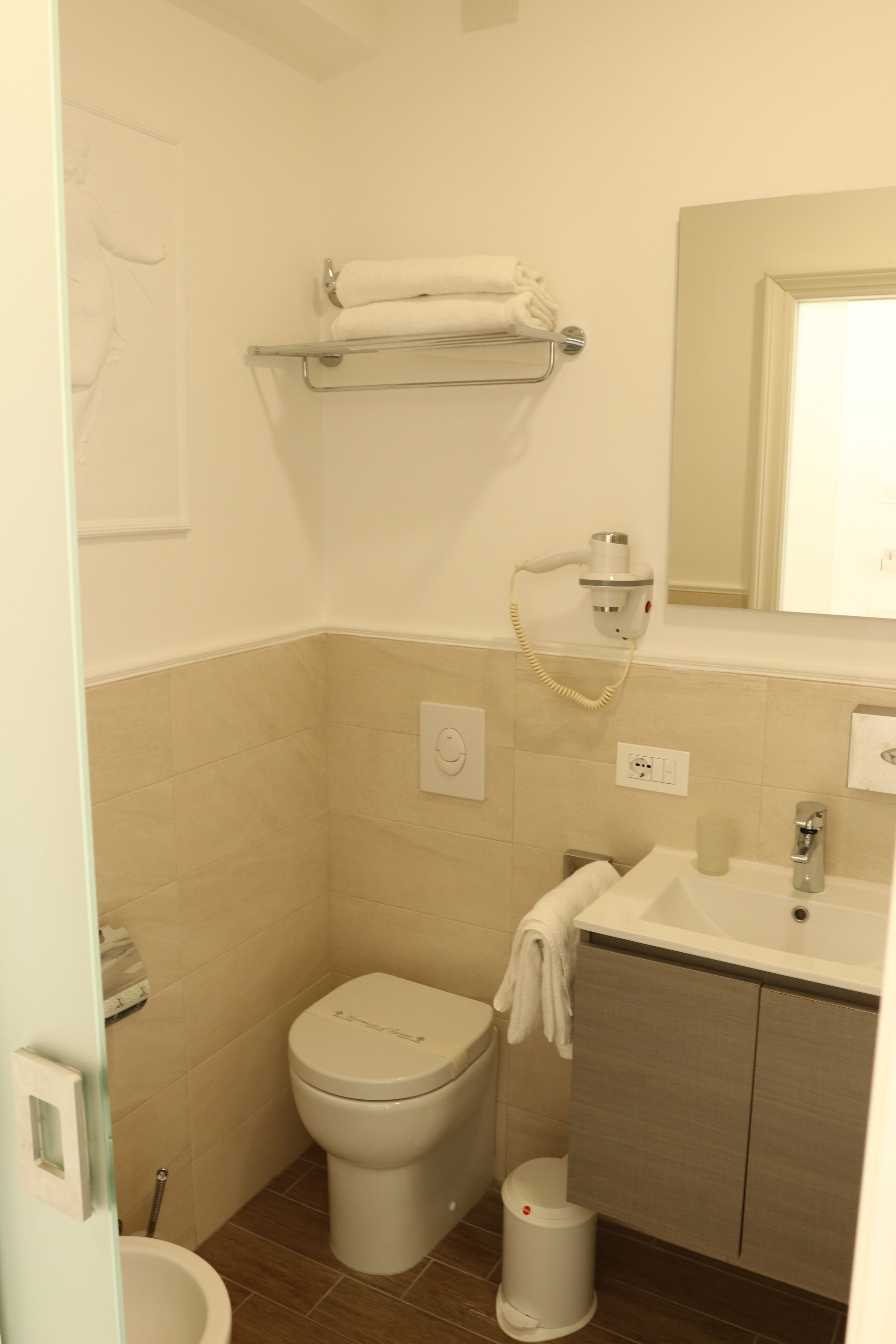 A small, clean bathroom with a toilet, sink, and towel rack.