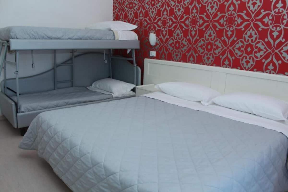 A bunk bed room with a lower bunk and a single bed, both with white bedding.
