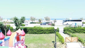 A view of a park with a colorful inflatable castle, a bus, and a gate.