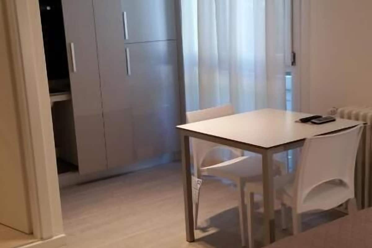 A hotel room with a bed, a table, chairs, a wardrobe, and a window with curtains.
