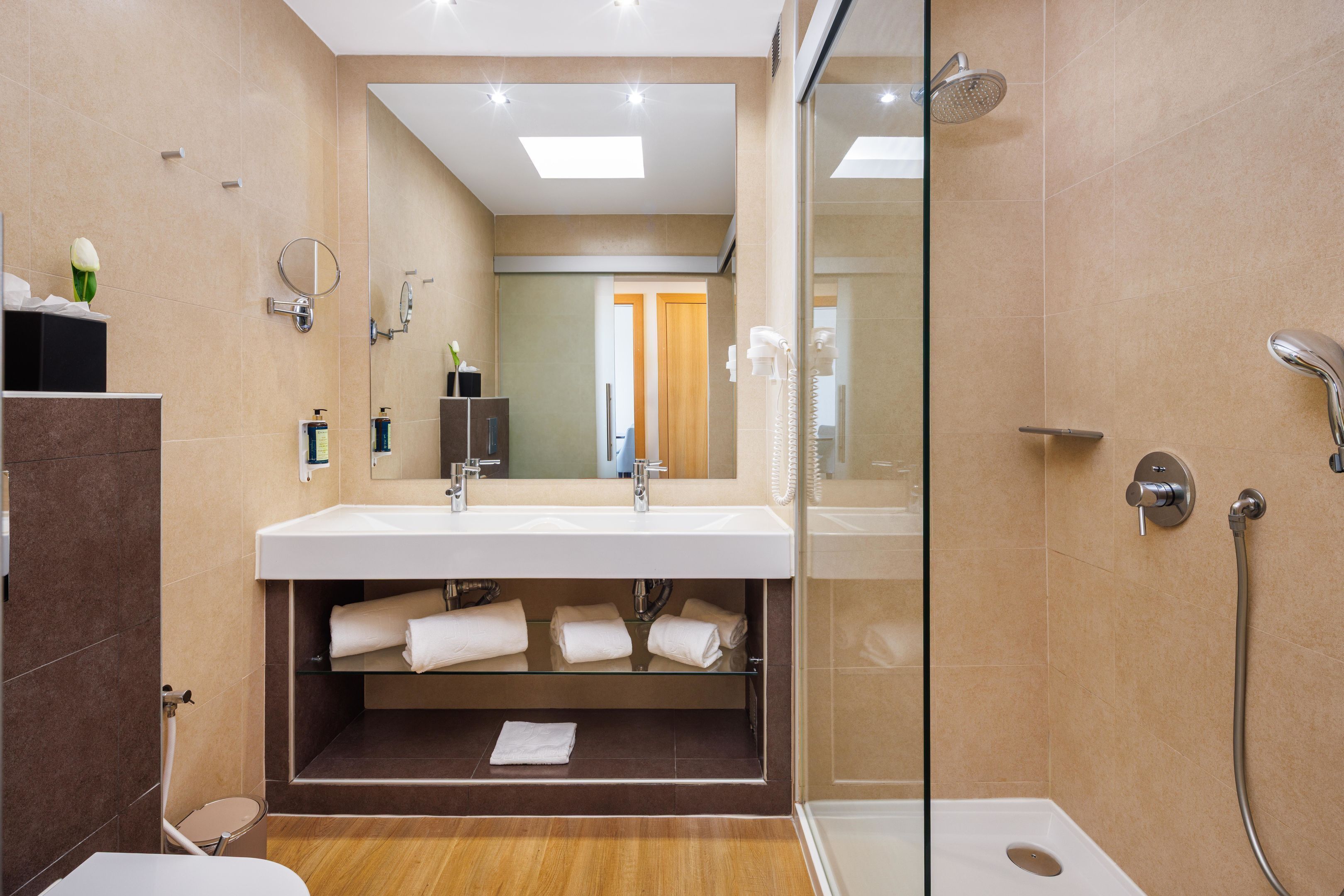 Une salle de bain moderne avec une douche à parois de verre, un meuble-lavabo à deux vasques et un miroir.
