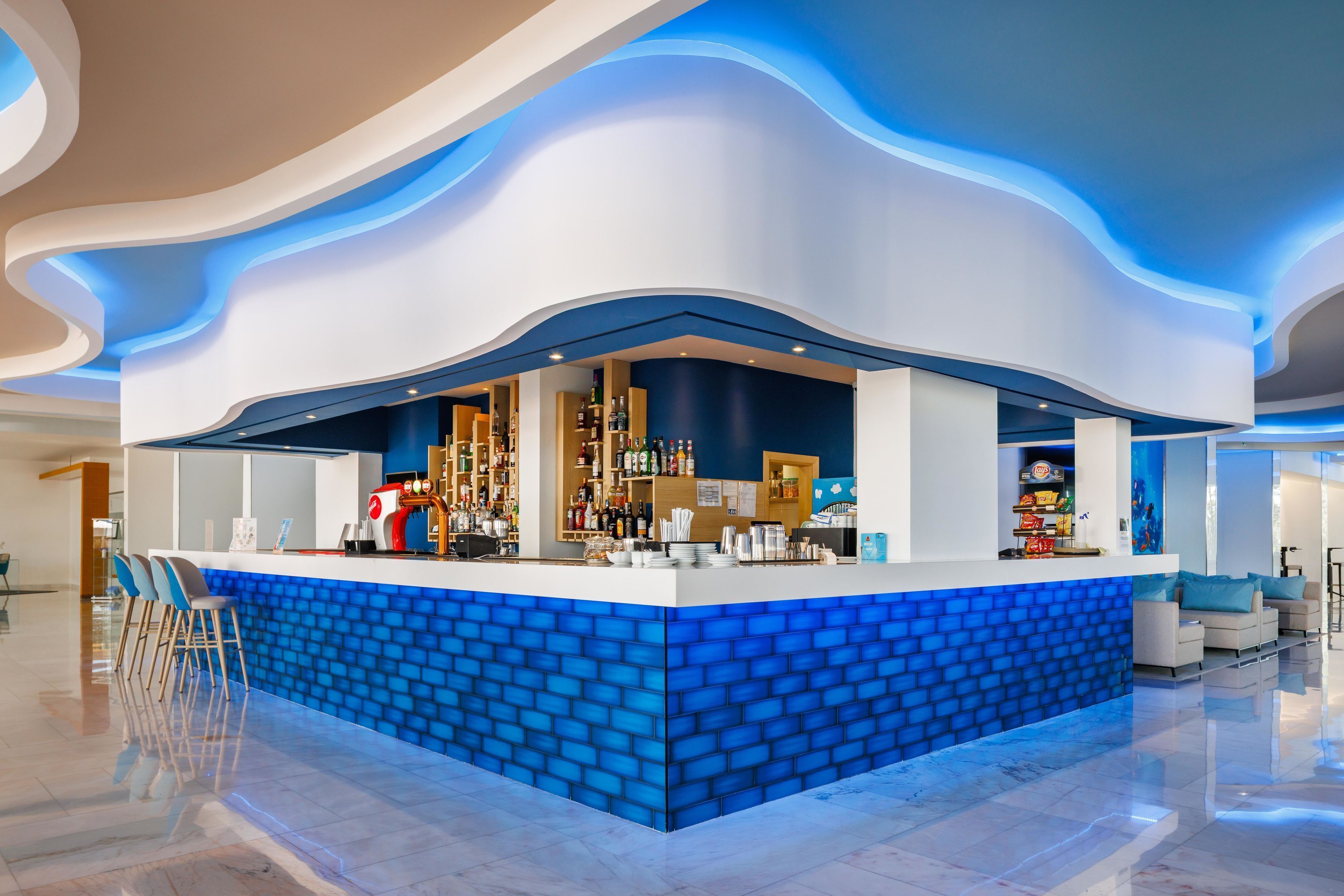 Un espace bar moderne, avec un décor en briques bleues, des tabourets de bar et une variété de bouteilles et de verres.