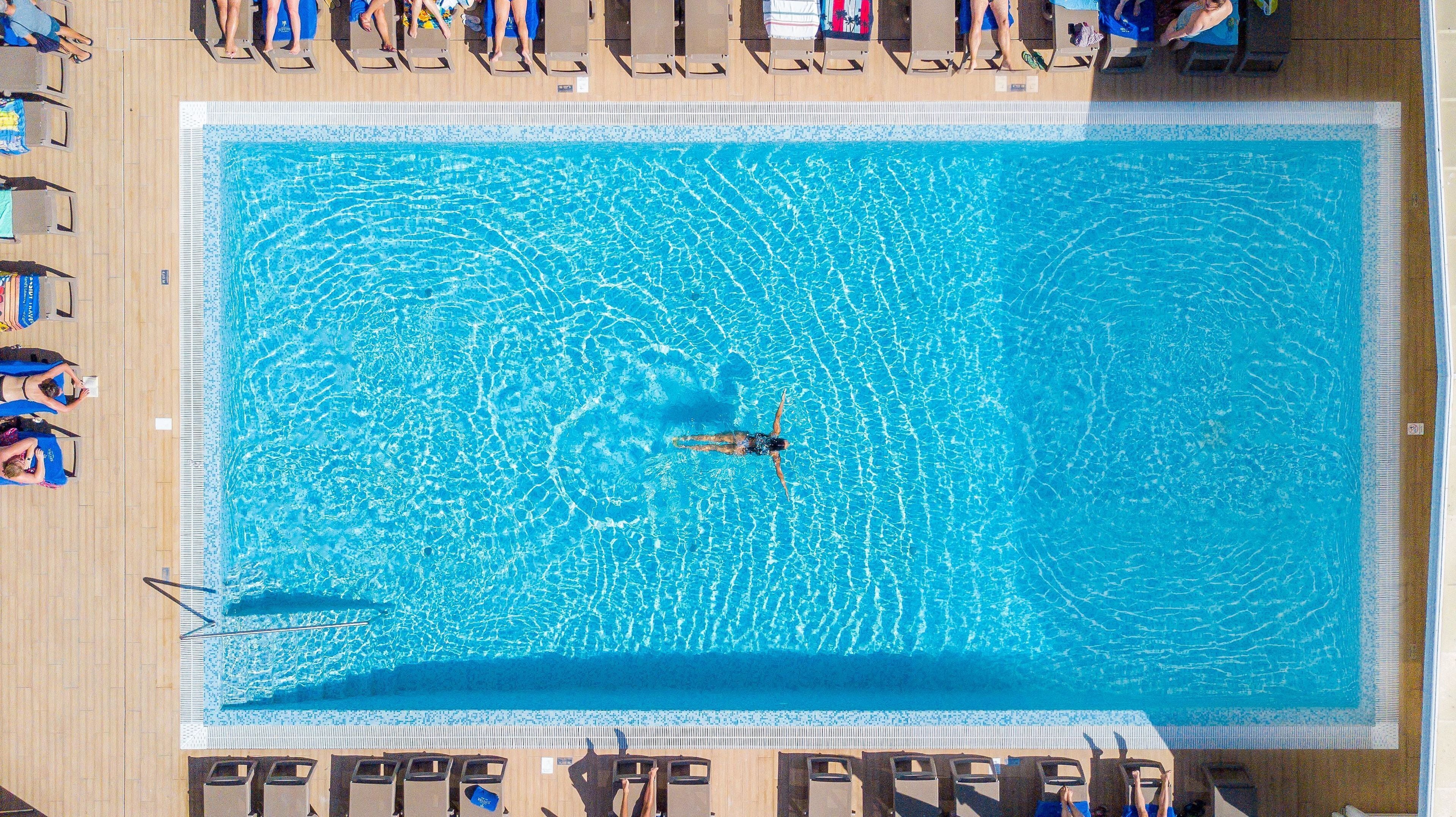 An aerial view of a rectangular swimming pool with a person swimming in the center.