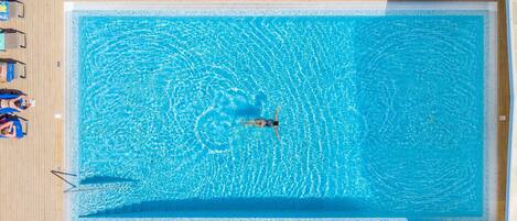 An aerial view of a rectangular swimming pool with a person swimming in the center.