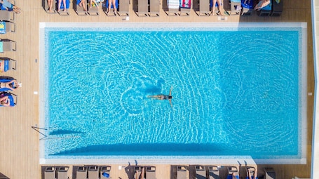 Una piscina techada, una piscina al aire libre, sombrillas