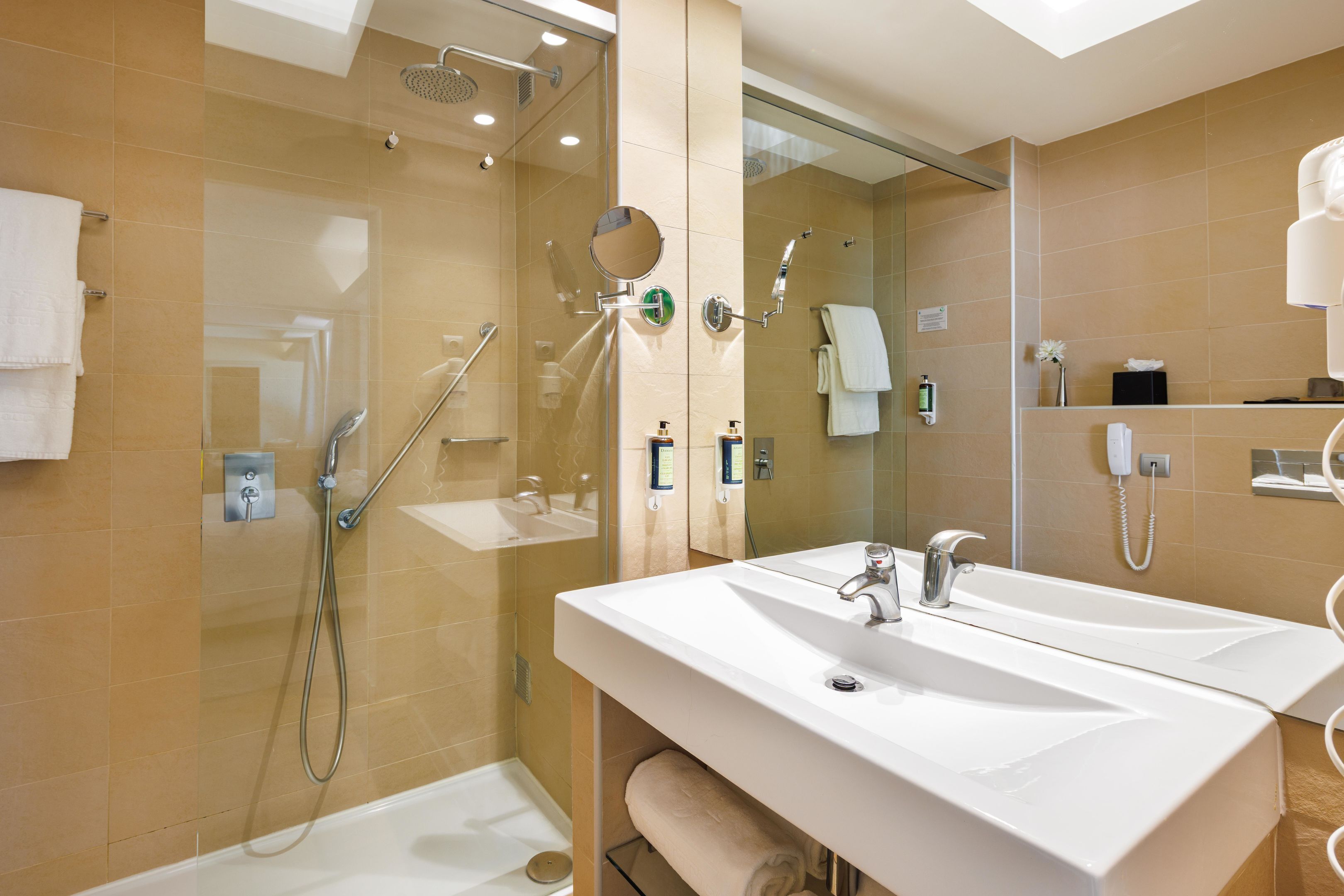 Ein modernes Badezimmer mit großem Spiegel, zwei Waschbecken, einer Duschkabine und einer Toilette.