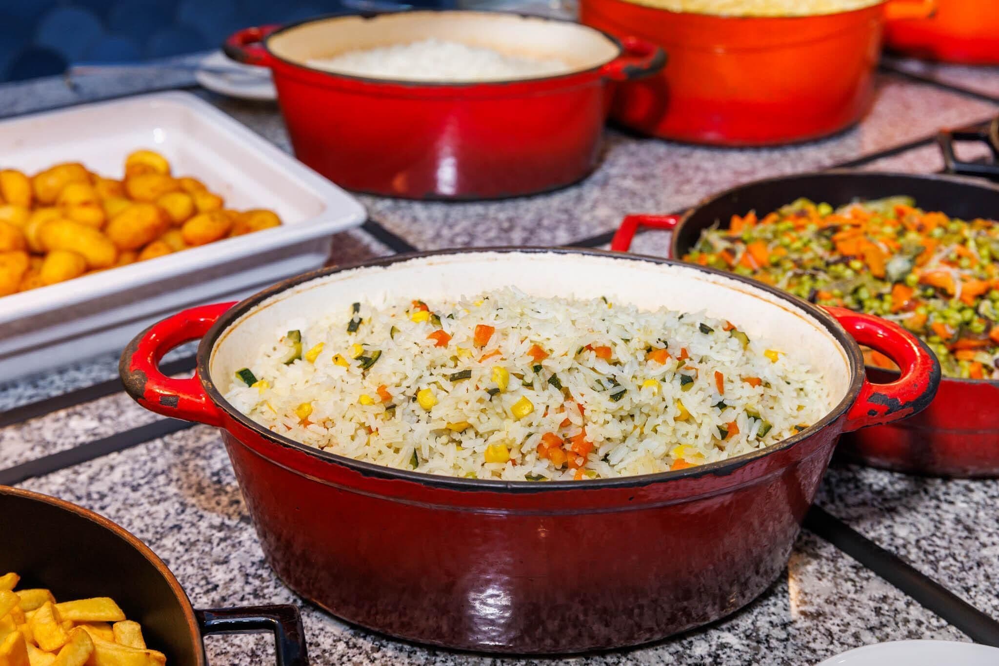 Una mesa de buffet con diversos platos, incluyendo arroz, verduras y alimentos fritos.