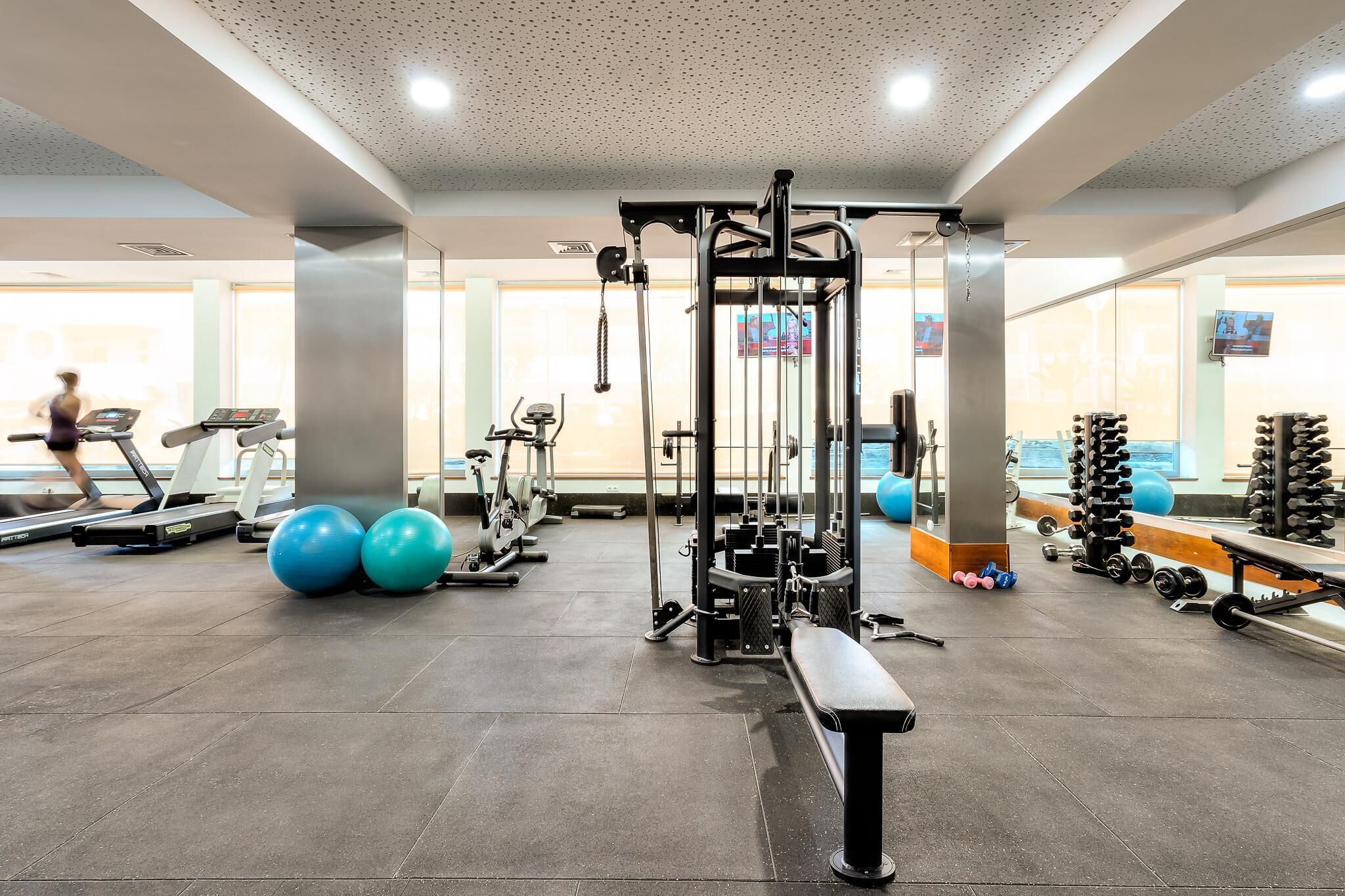 A gym with treadmills, exercise balls, and weightlifting equipment.