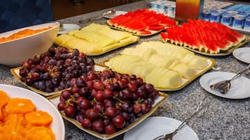 Un buffet proposant une variété de fruits et un saladier rempli de tranches d’orange.