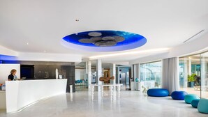 A modern hotel lobby with a reception desk, seating area, and a unique ceiling design. - Jupiter Algarve Hotel - Beach & Spa (Portimão)