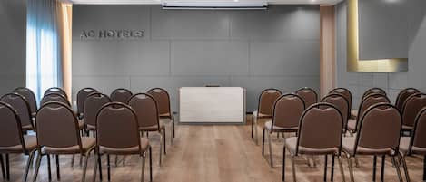 Un salón de conferencias con una larga mesa y filas de sillas orientadas hacia una recepción.