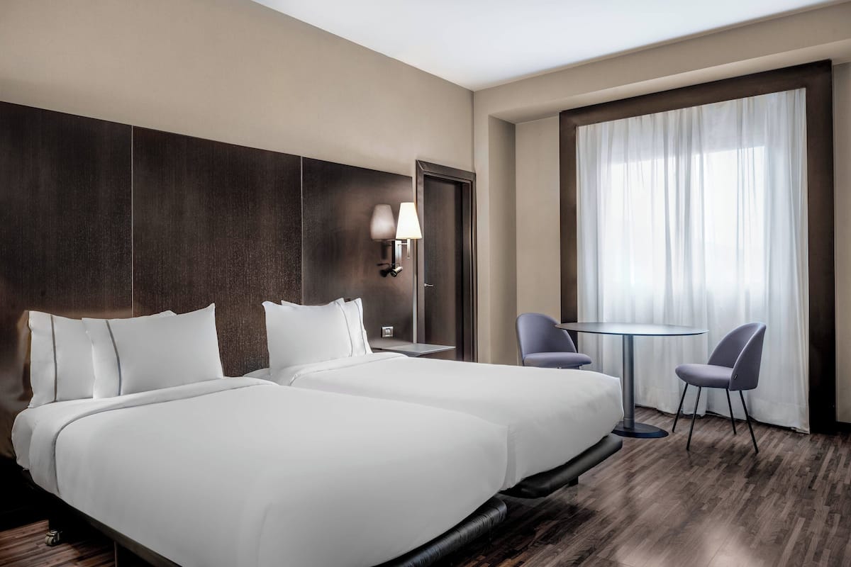 Une chambre d’hôtel avec un grand lit, un bureau, une chaise et une fenêtre avec des rideaux.