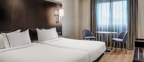 A hotel room with two large beds, a desk, a chair, and a window with curtains.