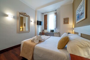 Una camera d'albergo con un letto, una scrivania, una televisione e un quadro appeso al muro.