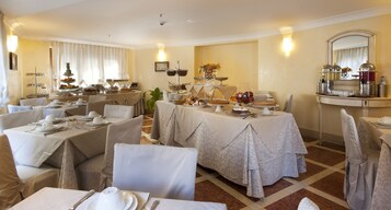 Zona pranzo con diversi tavoli apparecchiati per un pasto, con un'ampia scelta di piatti e un'organizzazione buffet.