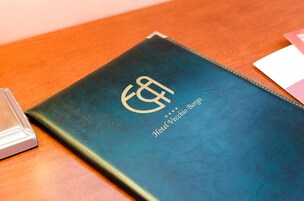 Un libro rilegato in pelle blu scuro con uno stemma dorato e la scritta "Hotel Vecchio Borgo".