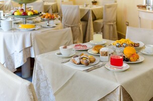 Una colazione con piatti di pasticcini, frutta e bevande su un tavolo.