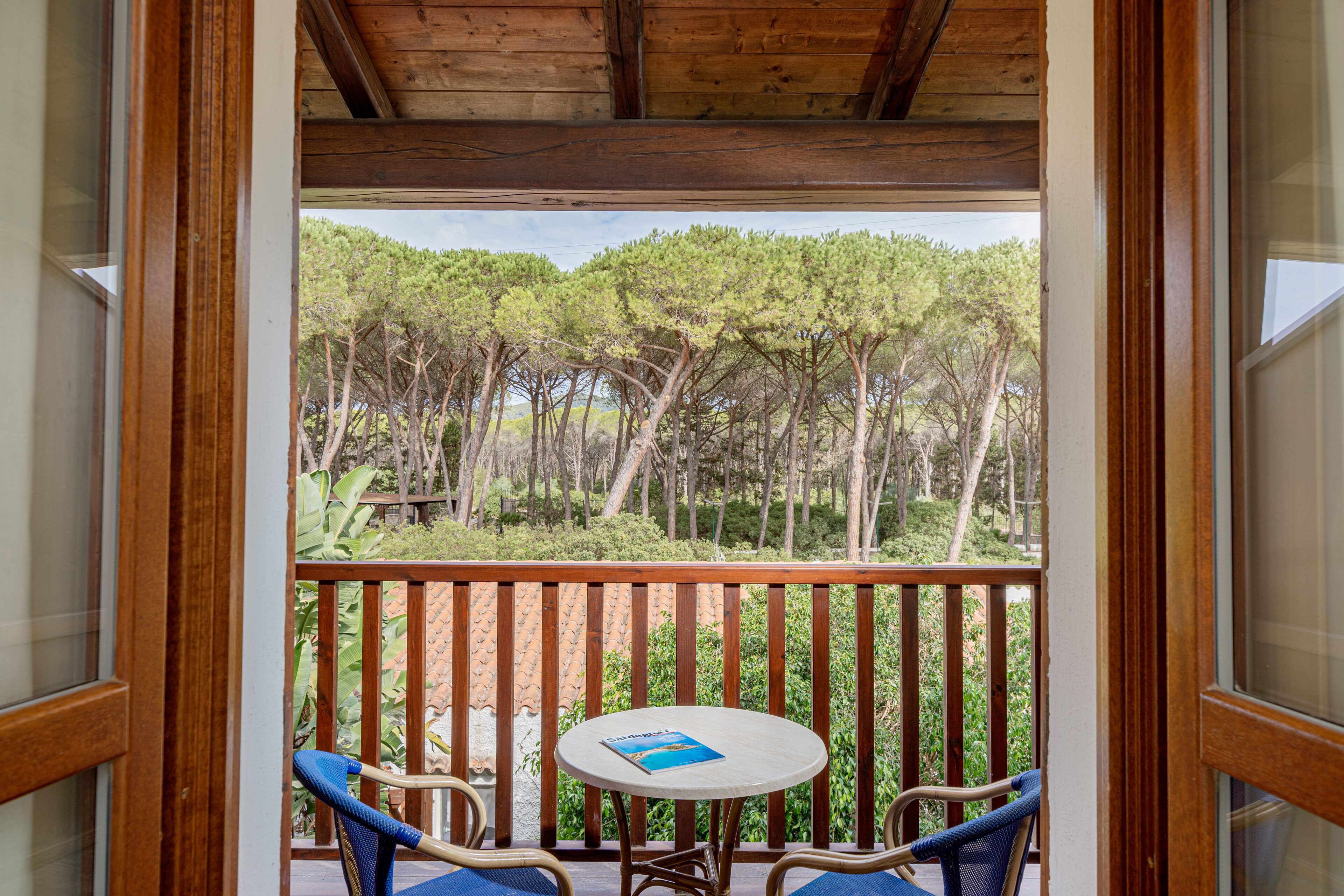 A balcony with wooden railings, a small round table, and two blue chairs.