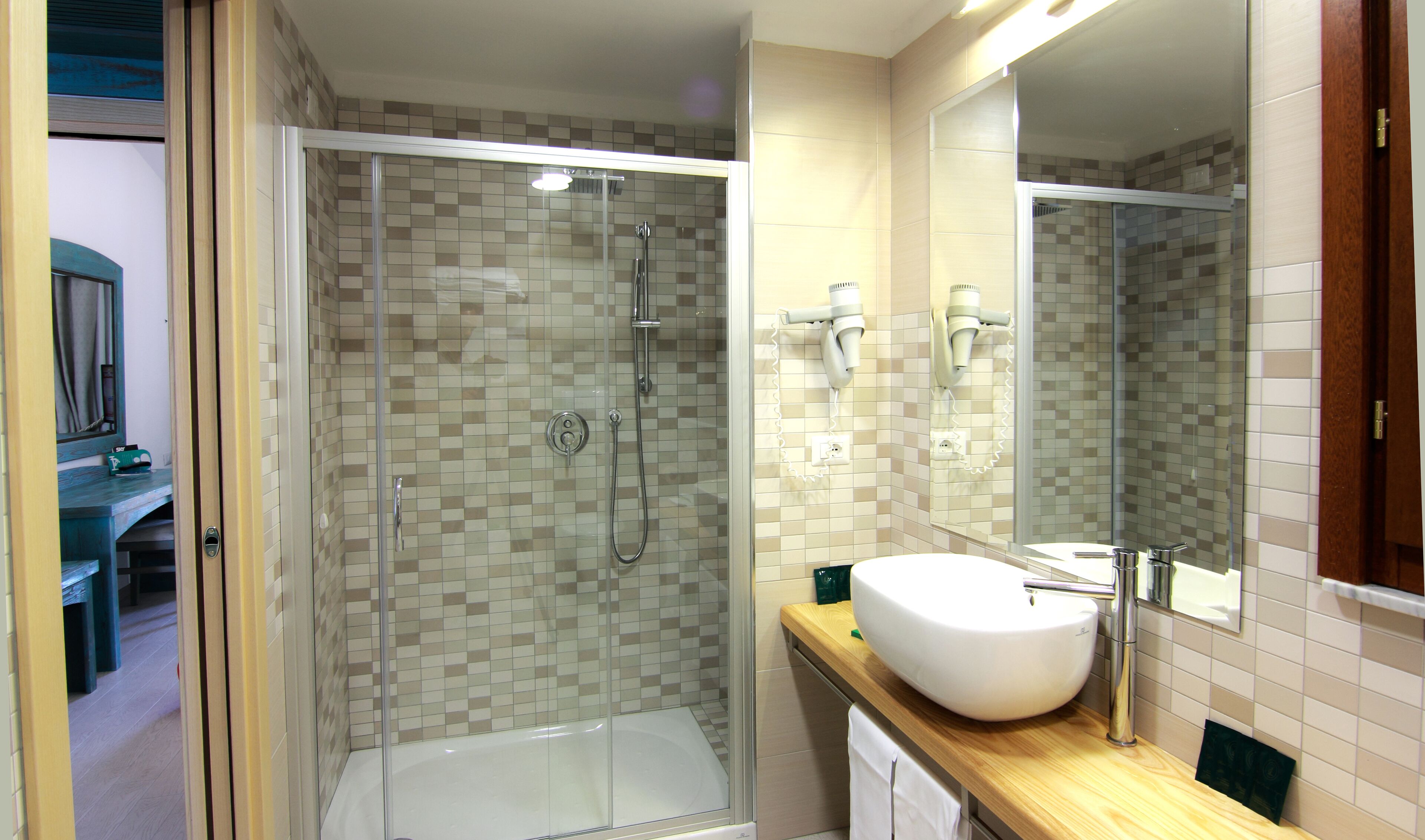 Un baño con ducha de vidrio, un lavamanos blanco y un espejo.
