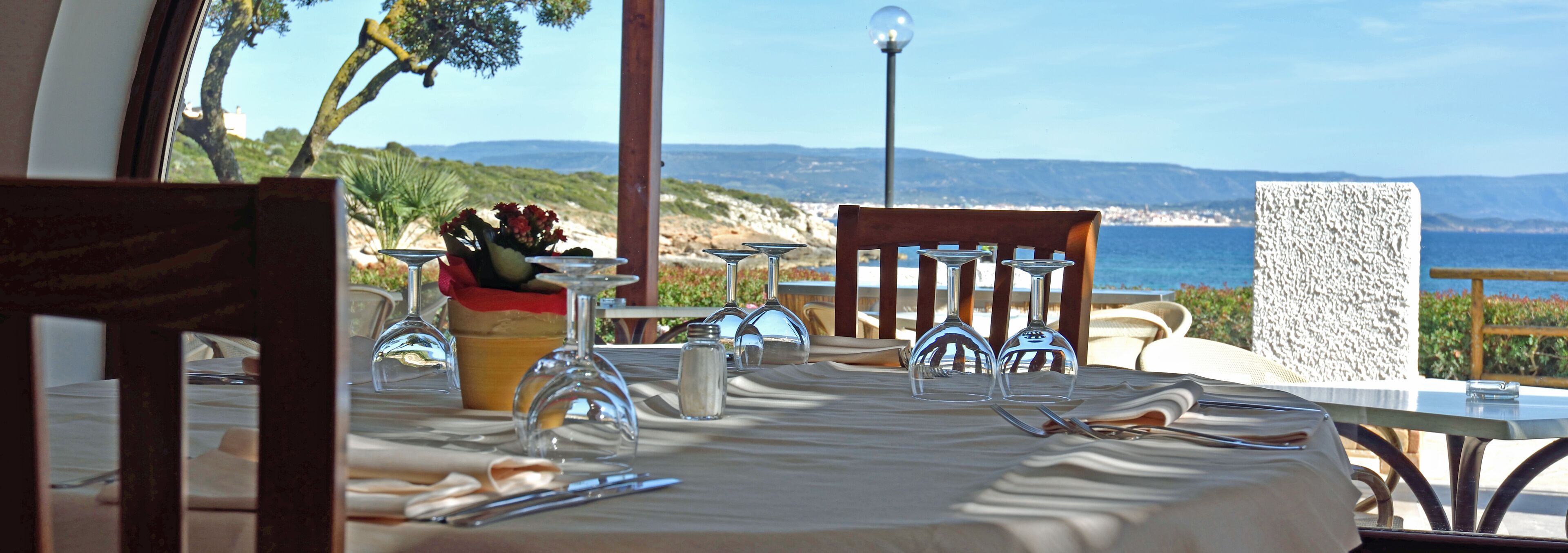 An outdoor dining area with a table set for two, overlooking a coastal landscape.