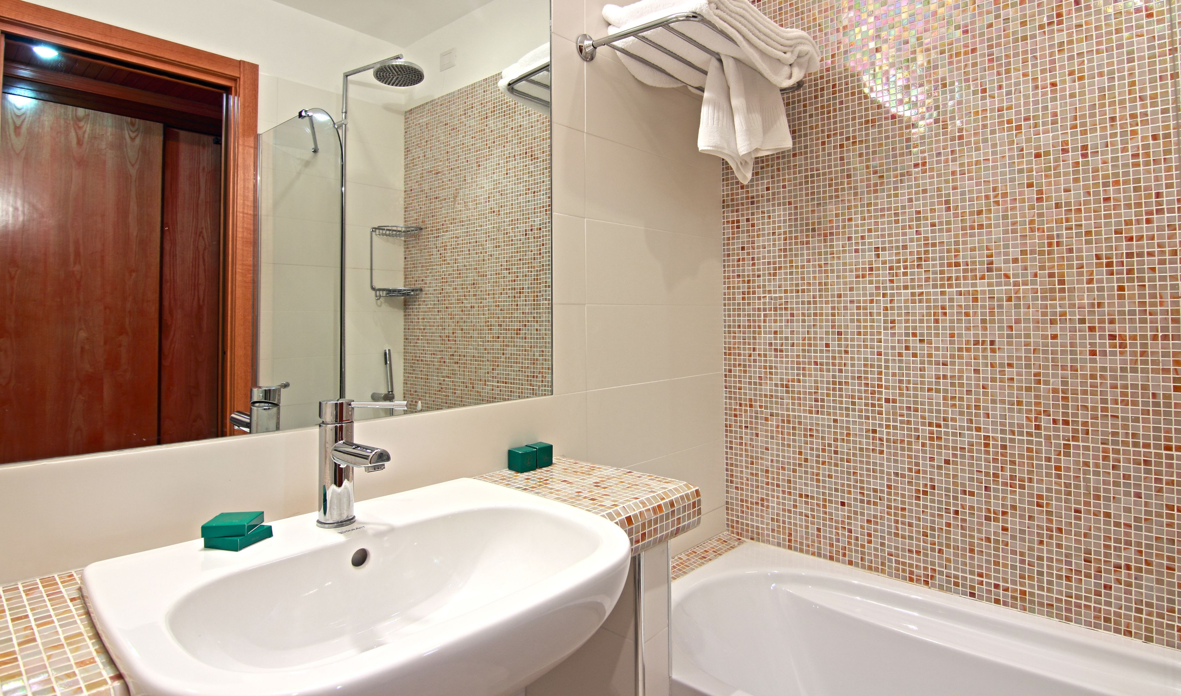 A bathroom with a white sink, a mirror, a shower, and a bathtub.