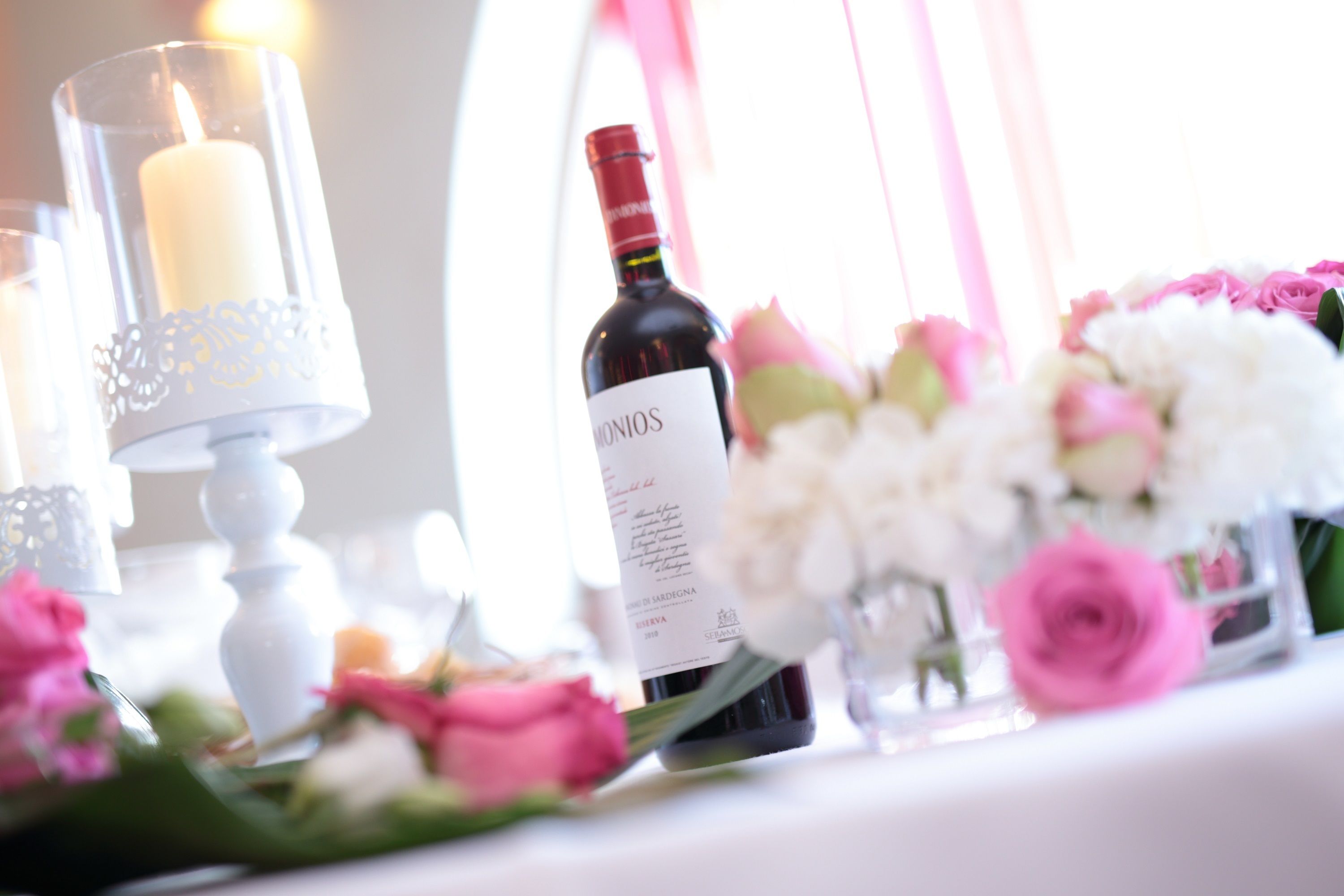 Une table avec une bouteille de vin, des bougies et des fleurs.