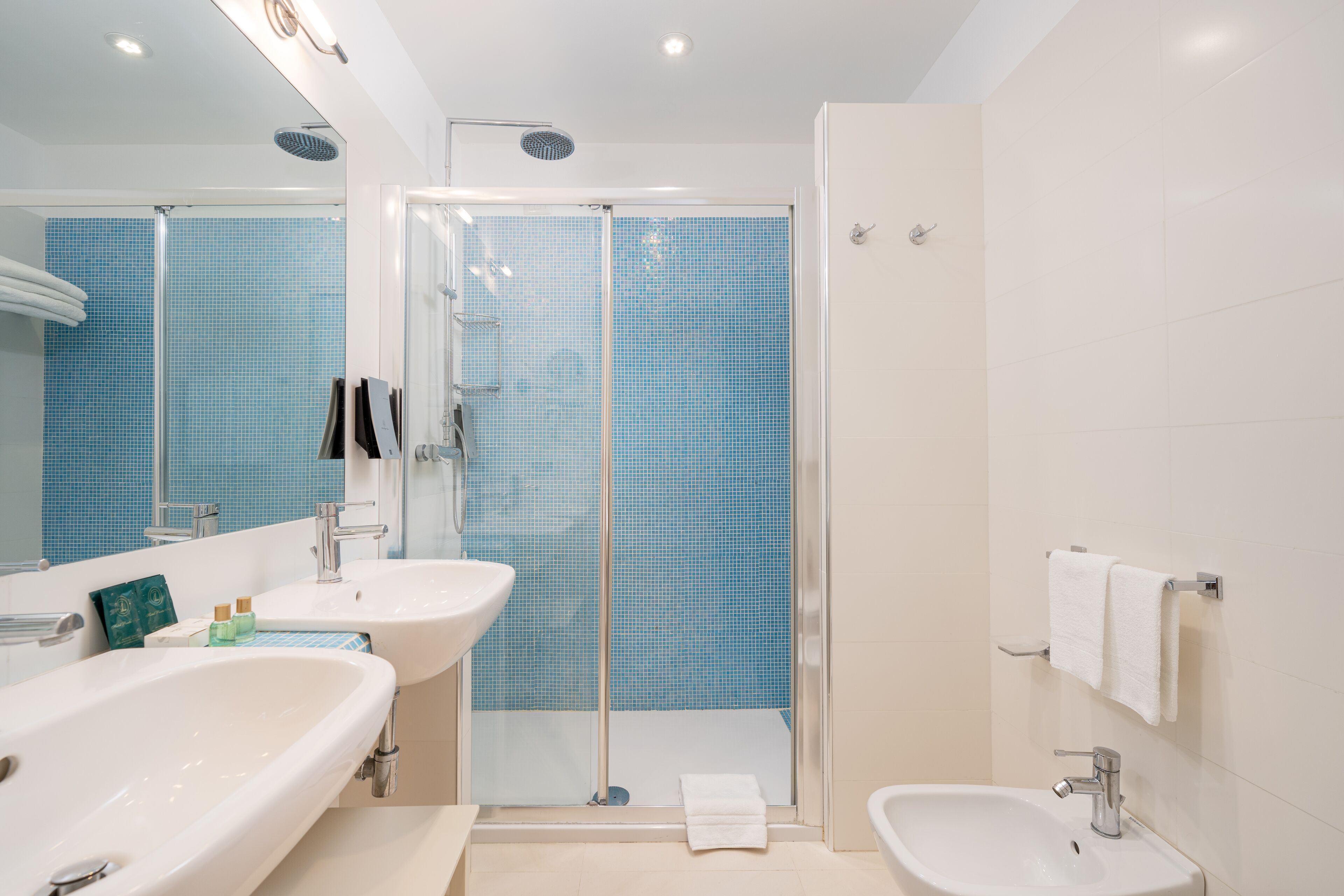 Une salle de bain moderne avec deux lavabos, une douche et un bidet.