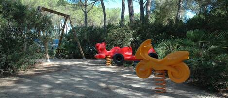 A playground with a swing set and a red and yellow seesaw.
