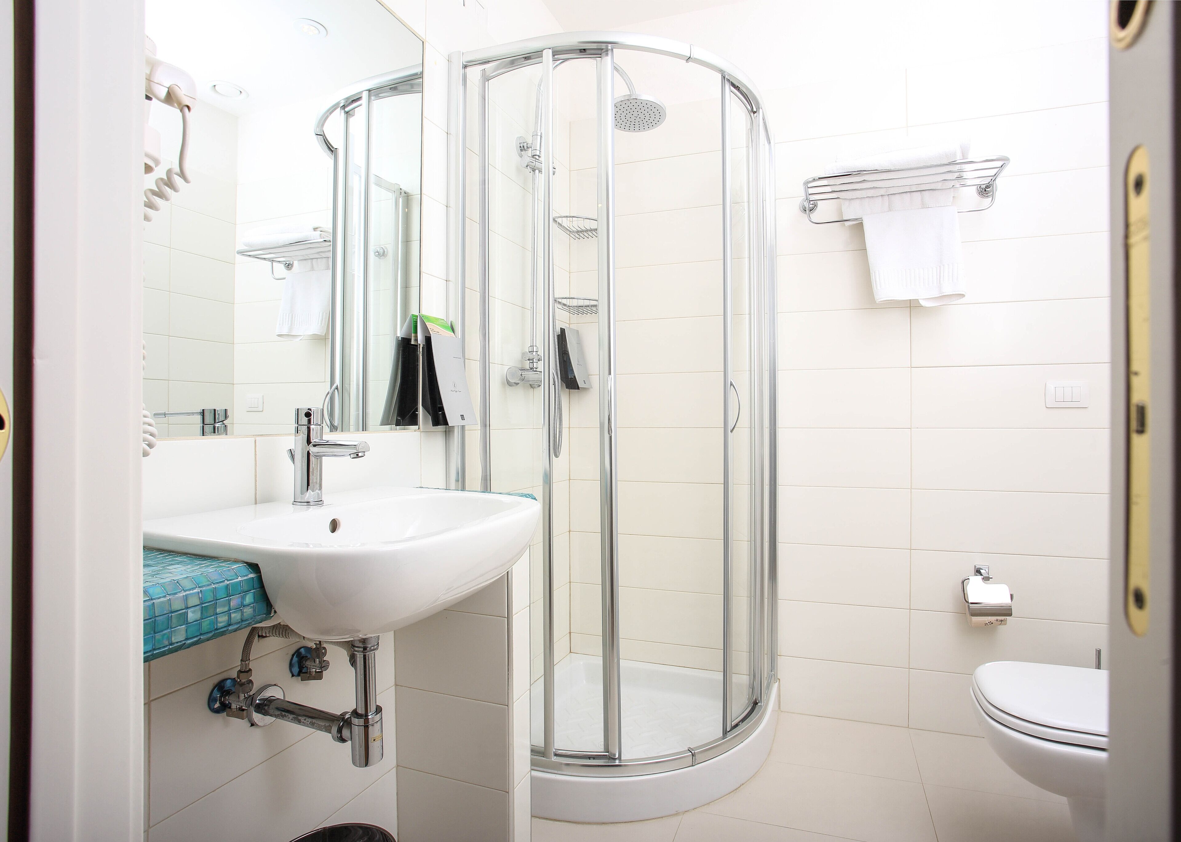 A modern bathroom with a glass-enclosed shower, a white sink, and a toilet.