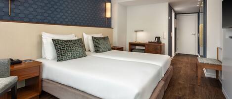 A hotel room with a large bed, two bedside tables, a desk, a chair, and a TV.