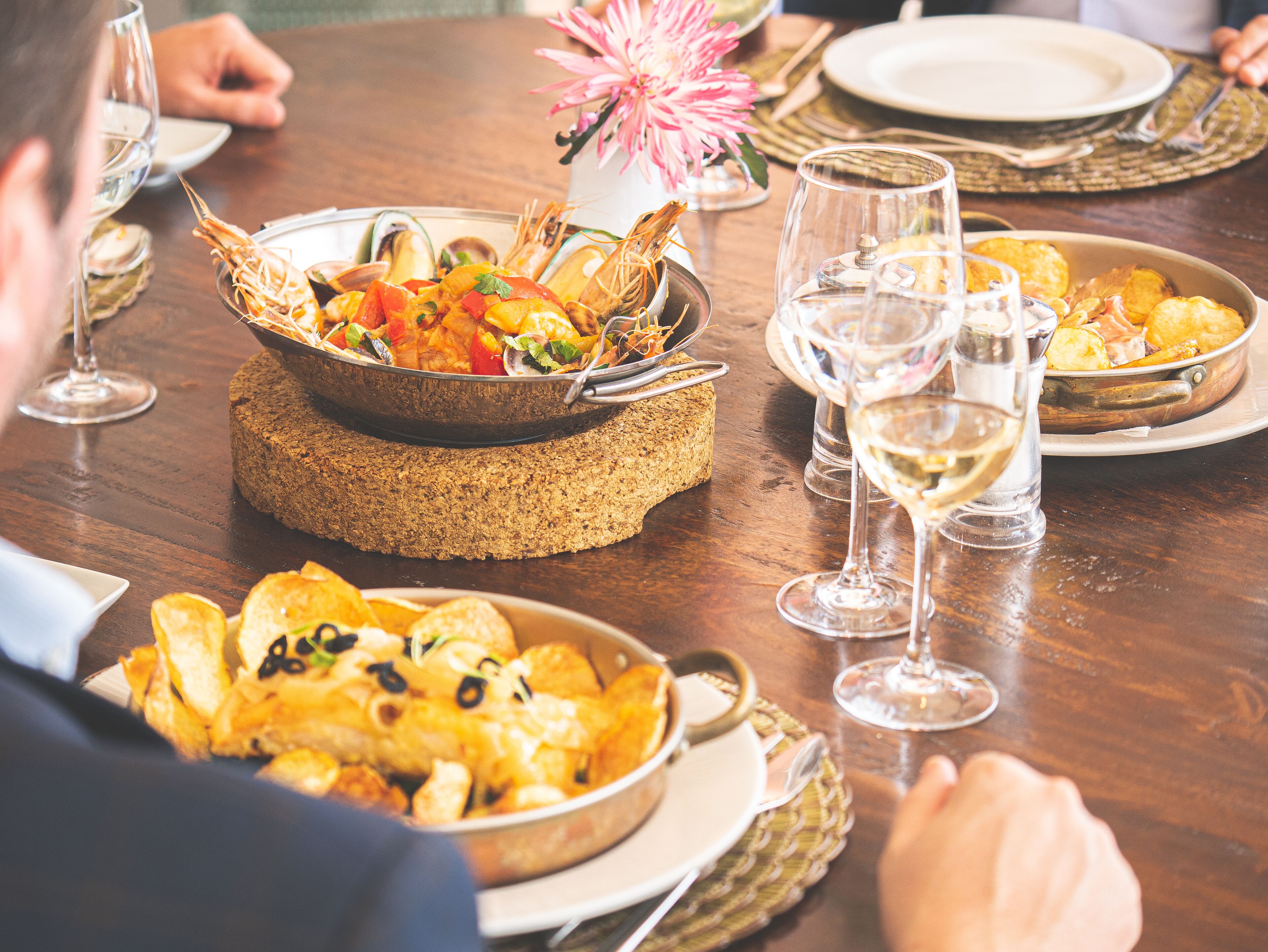 Una mesa de comedor con varios platos, copas de vino y una pieza central.