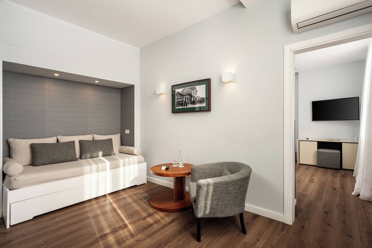A modern room with a sofa, a round wooden table, a chair, a framed picture, and a TV.