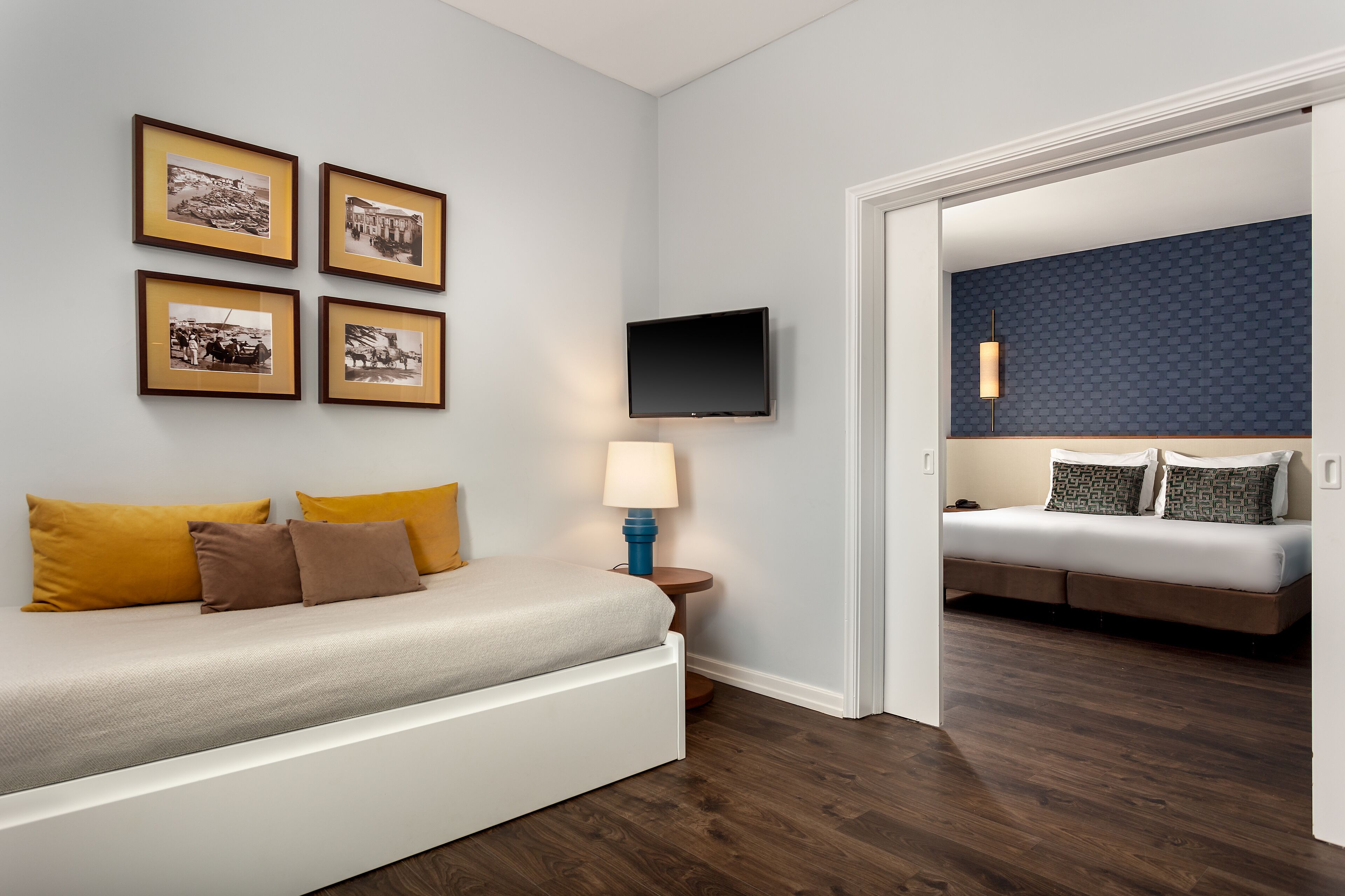 Un dormitorio moderno con cama, televisor y cuadros en la pared.