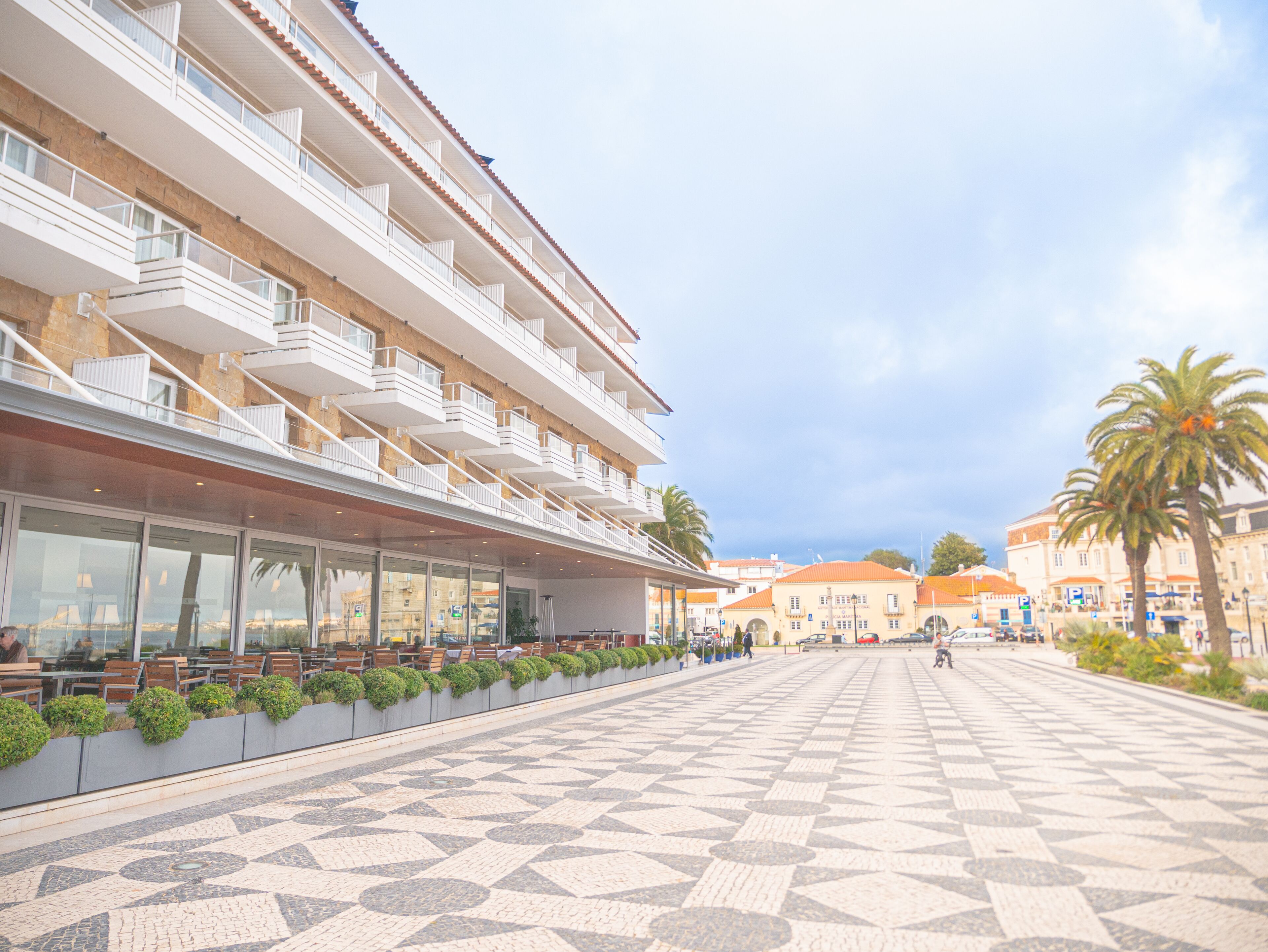 Un hotel con numerosi balconi, area salotto all'aperto e un vialetto lastricato.