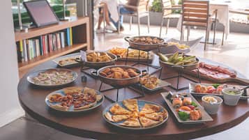 Une table ronde sur laquelle sont disposés divers aliments, notamment des pizzas, des sushis et des amuse-gueules.
